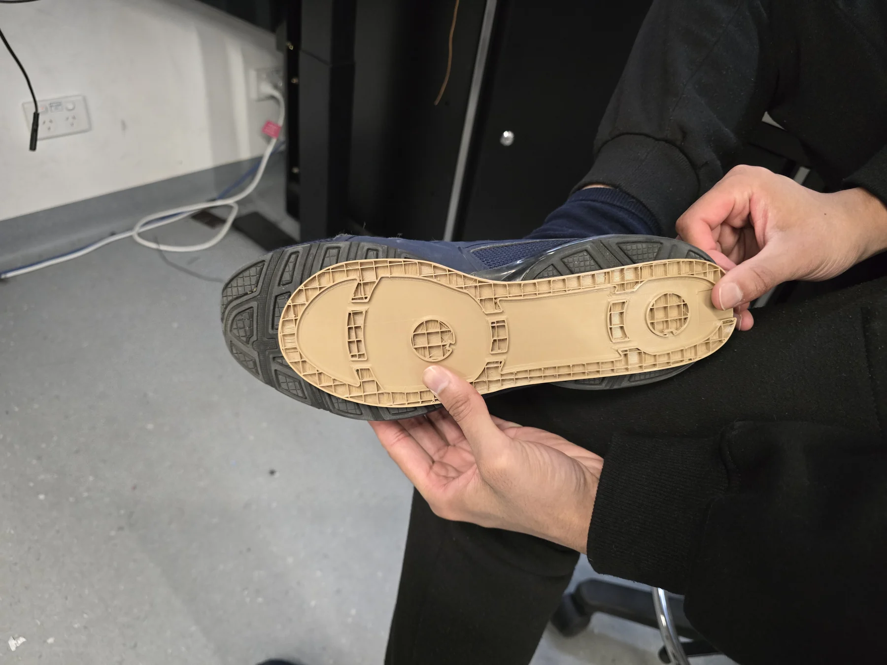 Hands comparing a printed insole housing with the underside of a shoe