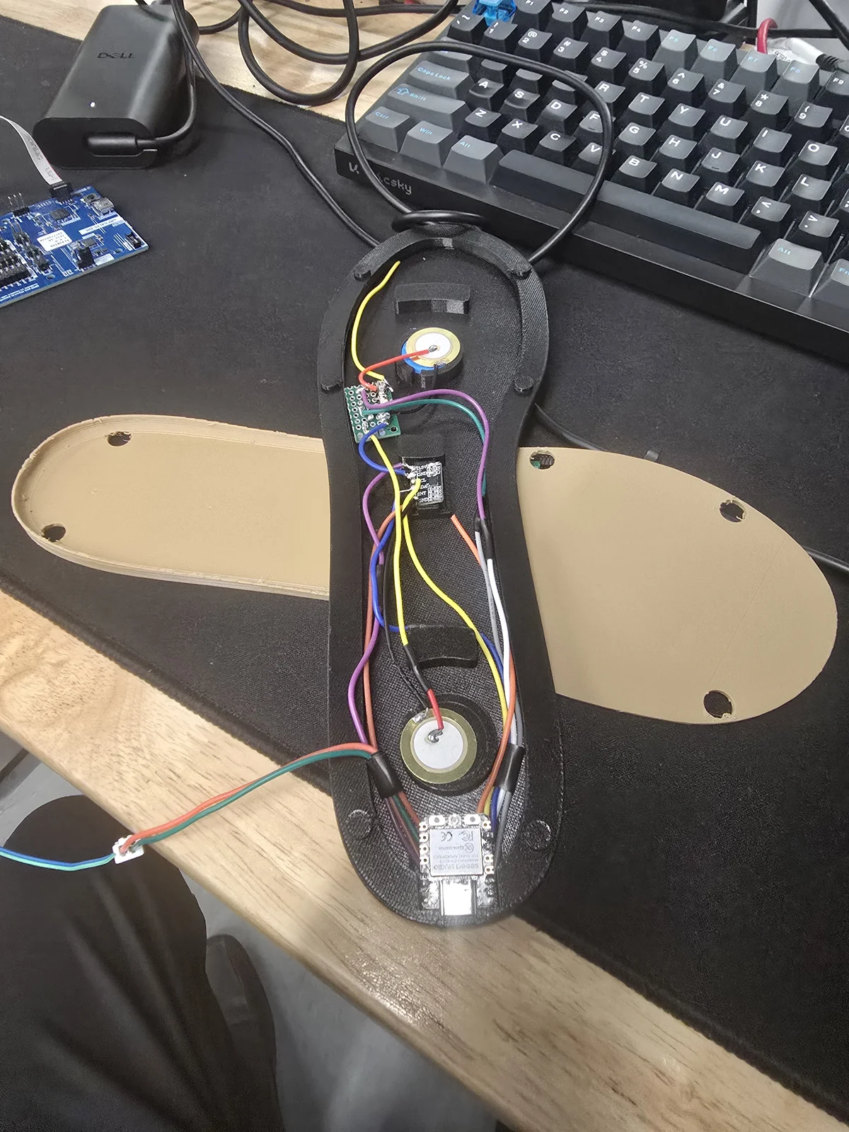 An instrumented black insole alongside earlier tan housings on the workbench